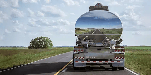 Camion-citerne sur une route ensoleillée. Neo Répartition Pétrole anticipe les besoins des stations-service, planifie le réapprovisionnement et optimise vos voyages pour éviter toute rupture de carburant.