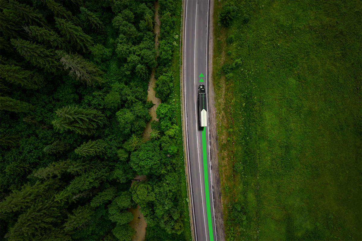 Vue aérienne d’un camion roulant sur une route entourée de forêt avec une flèche verte intégrée, illustrant Neo TMS – Solution complète pour optimiser la répartition, la paie des chauffeurs et les coûts d’énergie du transport routier.